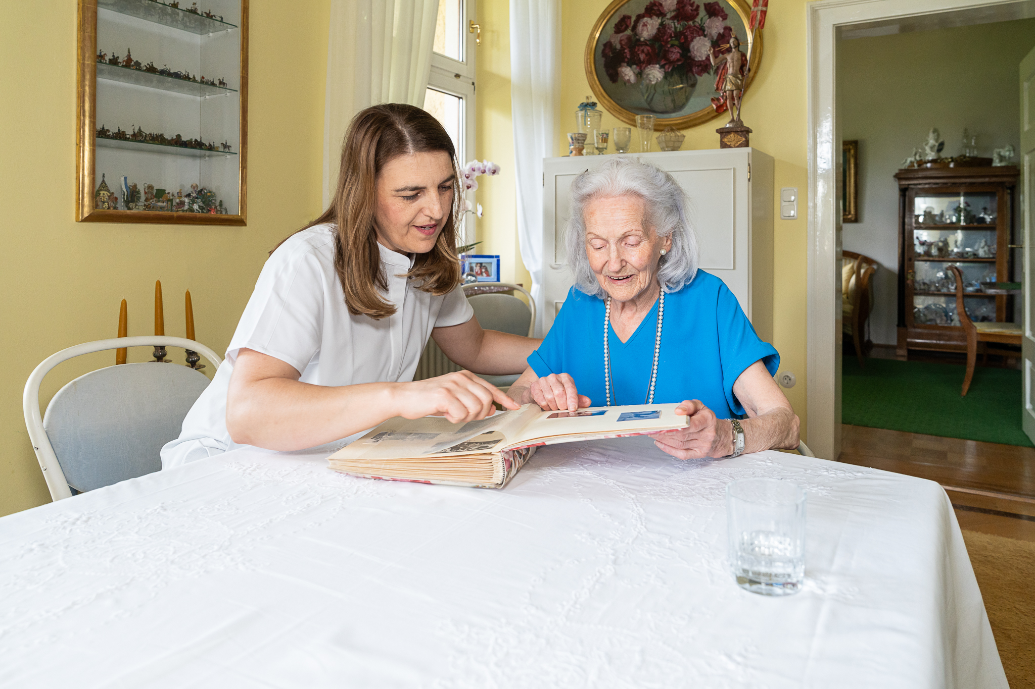 Biografiearbeit: Pflegekraft und Seniorin lesen/sehen gemeinsam ein Buch