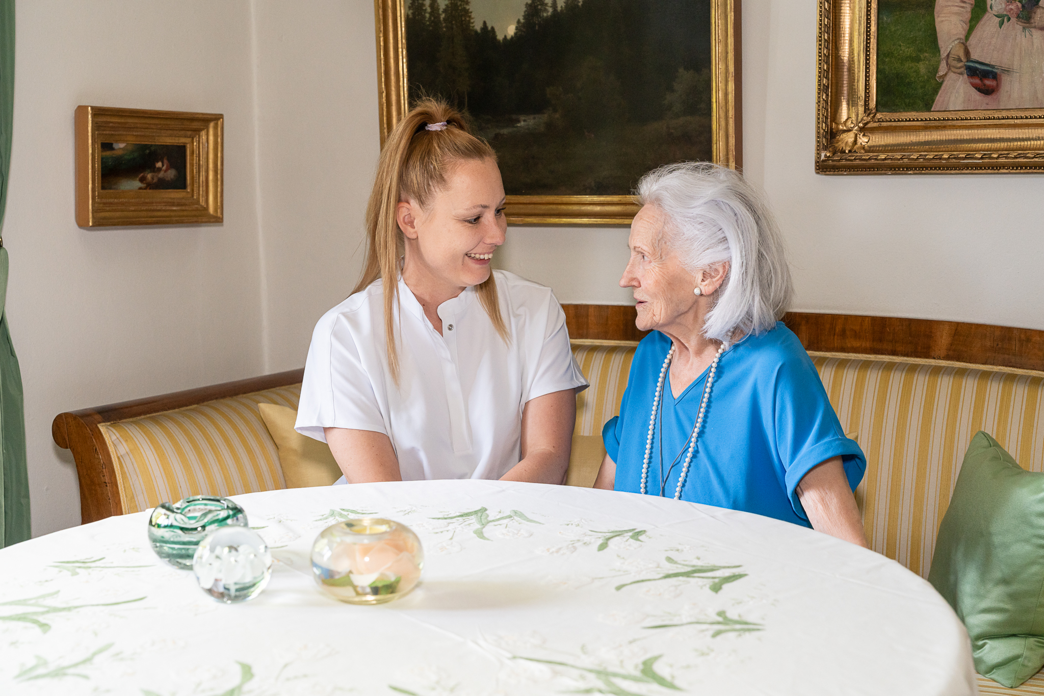 Bewegungsübungen: Pflegekraft mobilisiert das Bein einer Seniorin im Sessel