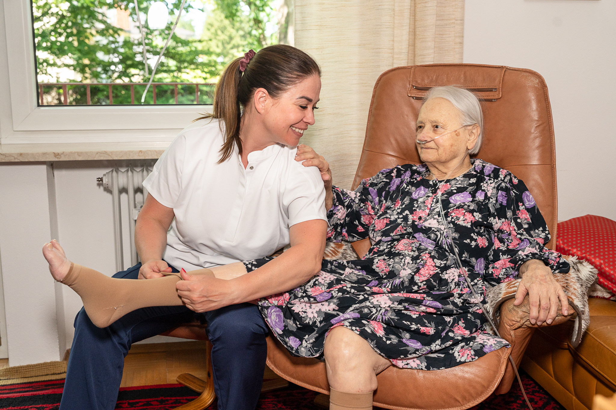 Mobilisation: Pflegekraft unterstützt Seniorin beim Aufstehen/Gehen