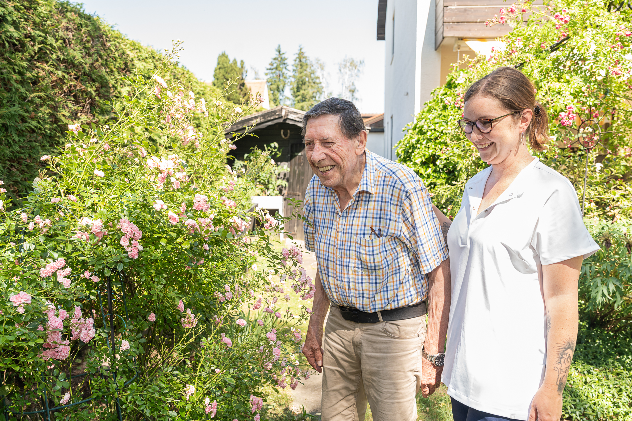 Spaziergang im Garten – Pflegekraft begleitet Senior