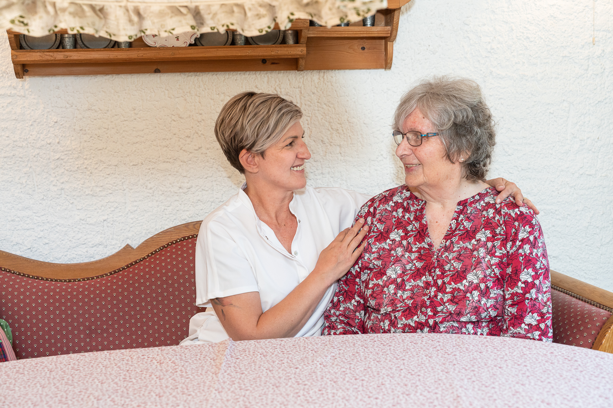 Herzliche Unterhaltung: Pflegekraft und Seniorin auf dem Sofa