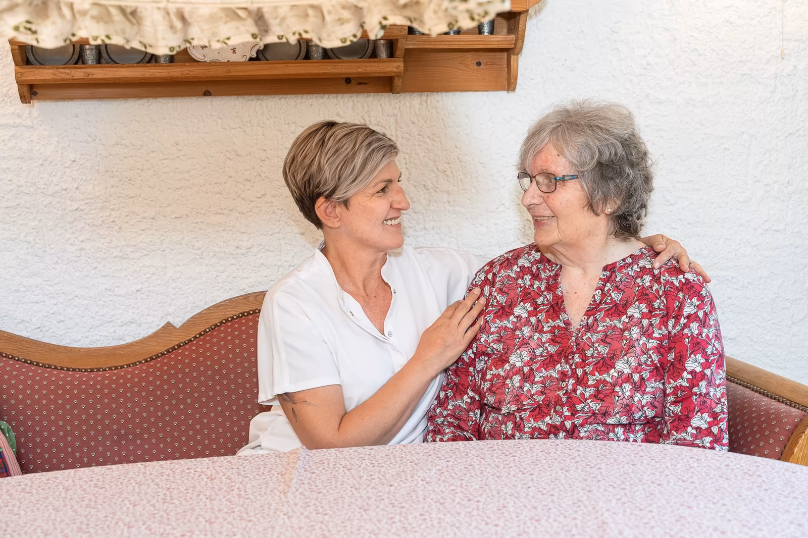 Herzliche Unterhaltung: Pflegekraft und Seniorin auf dem Sofa